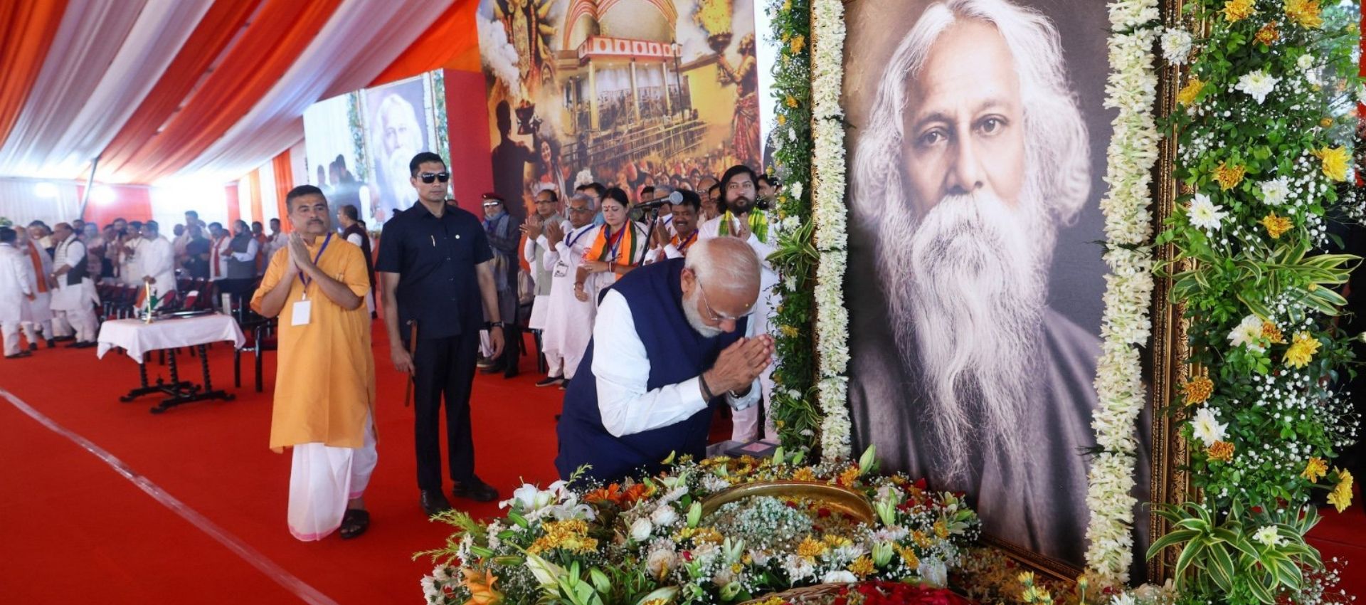 The image shows Prime Minister Narendra Modi bowing before the portrait of Rabindranath Tagore. West Bengal Chief Minister Suvendu Adhikari can be seen with his hands folded in the background.
