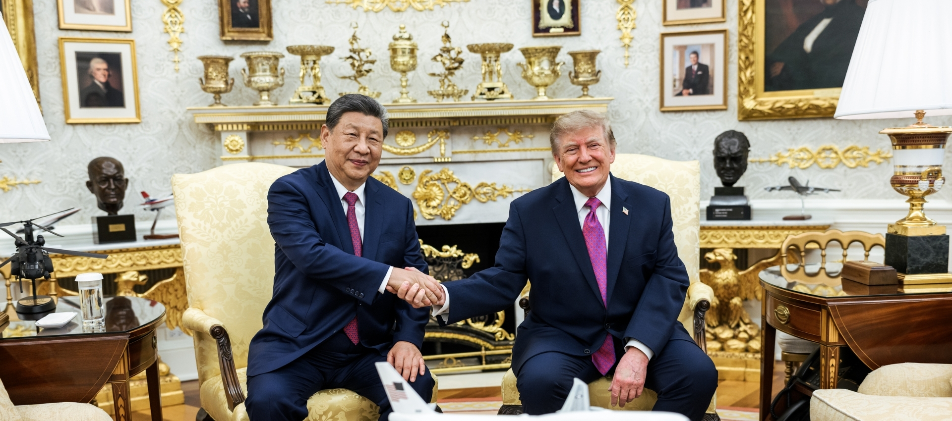Chinese President Xi Jinping and US President Donald Trump shake hands while seated in an ornate room at the White House, with diplomatic portraits can be seen in the background.