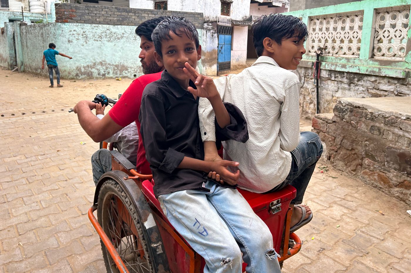 The image shows children sitting in Waseem’s motorised tricycle.
