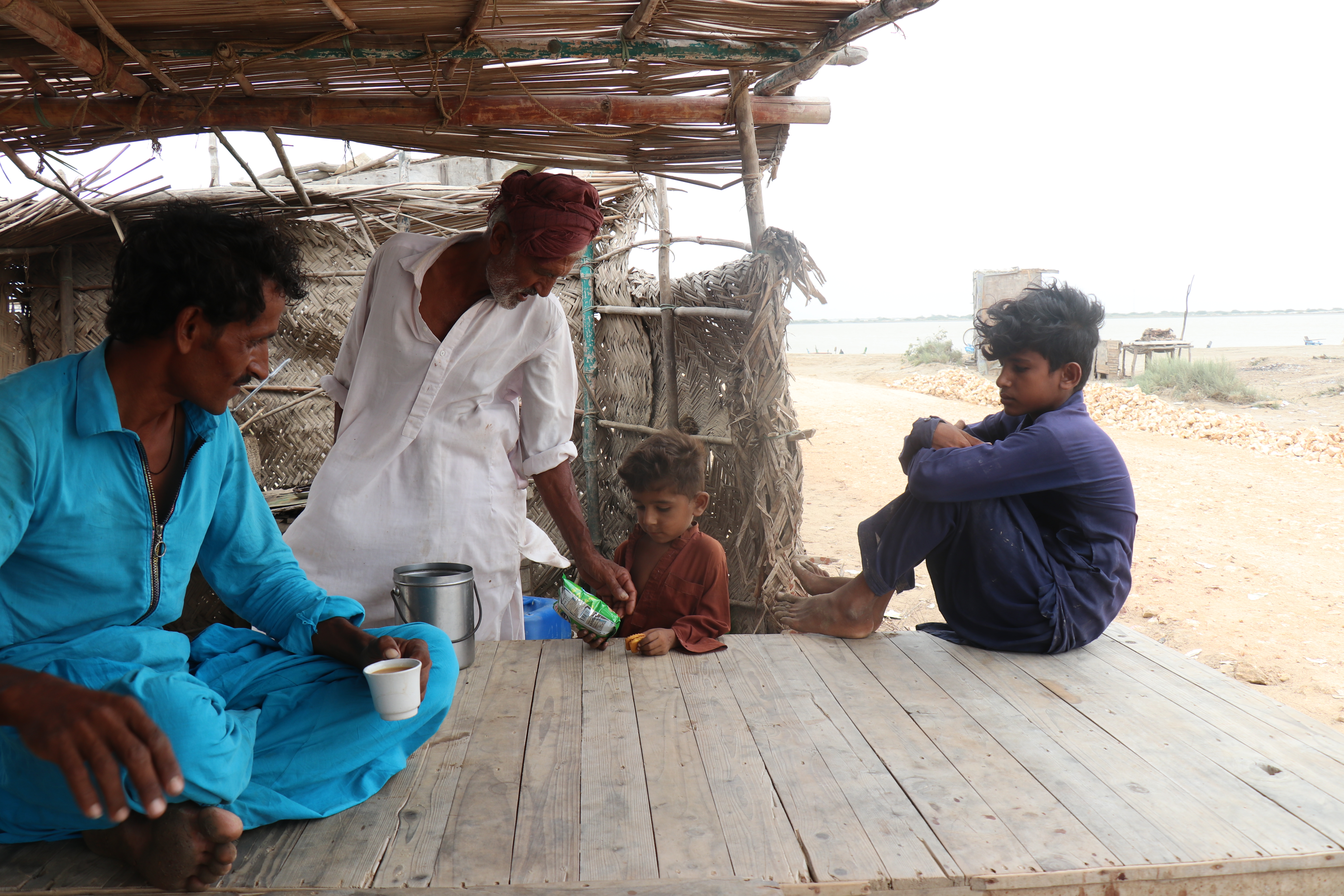 The image shows men waiting Men wait near a tea stall in the delta.